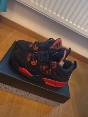Nike Air Jordan 4 Red Thunder - Priset kan diskuteras, sko lådan tillkommer även. Säljer ett par Nike Air Jordan 4 sneakers i svart och rött med klassisk mesh och detaljer på sidorna. Skorna har snörning, platt sula och rund tå. Tungan är röd med Air Jordan-märke. Perfekt för dig som vill ha en ikonisk och snygg sneaker med streetkänsla.