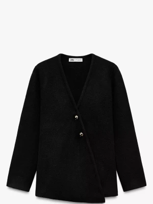 Svart omlott cardigan jacka från Zara - Svart cardigan jacka från Zara med omlott-design och två silvriga knappar framtill. Jackan har lång ärm och är tillverkad i ett mjukt material som känns lite ulligt. Perfekt för dig som gillar stilrena och enkla plagg med en twist.