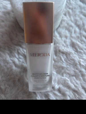 Meroda Changing Foundation 30ml - Foundation från Meroda som anpassar sig efter hudens färg och textur. Passar ljusa till medelljusa hudtoner. Kommer i en stilren glasflaska med roséguldfärgat lock. Volymen är 30 ml och formulan är flytande. Ny pris cirka 380