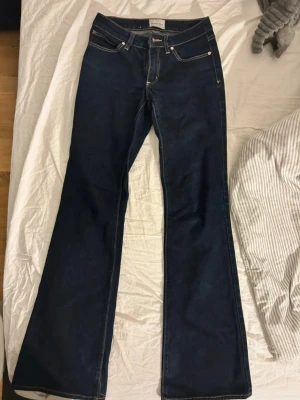 ABrand Alice Tall Jeans - Snygga mörkblå jeans från ABrand med klassisk bootcut passform. Jeansen har kontrastsömmar, fem fickor och en liten Replay-logga på bakfickan. Perfekt för dig som gillar retrovibbar och vill ha ett par jeans med lite extra sväng i benen.  ⚠️ OBS! använd fåtal gånger.