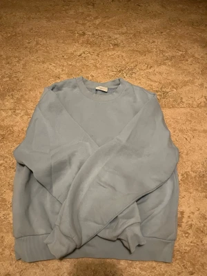 Ljusblå sweatshirt  - Säljer en stilren ljusblå sweatshirt från Gina Tricot med rund hals och ribbade muddar vid ärmslut och nederkant. Perfekt för chill dagar och enkel att matcha med jeans eller mjukisbyxor. Materialet är mjuk bomull som känns skönt mot huden.