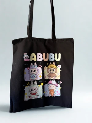 Svart shoppingväska med LABUBU-tryck - Cool svart shoppingväska med färgglatt LABUBU-tryck och söta tecknade figurer på framsidan. Väskan har långa handtag och är gjord i mjuk bomull, perfekt att slänga över axeln när du drar ut på stan eller till skolan. Rymmer allt du behöver och har en lekfull vibe.