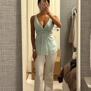 Ljusblå ärmlös omlottopp - Säljer en ljusblå ärmlös omlottopp med djup v-ringning och markerad midja med dekorativt band. Man knyter banden i bak på ryggen. Skitsnygg sommar färg! 