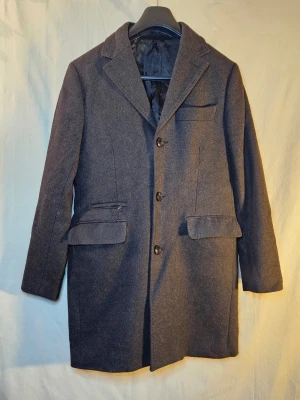 Brun rock | Brothers - Riley Shelby - Snygg brun rock från Brothers | Riley - Shelby med italienskt tyg från Mario Bellucci. Tyget är ull och cashmire! Klassisk design med tre knappar framtill, krage och flera fickor, både med lock och dragkedja. Fodrad insida i brunt tyg, perfekt för höst och vinter. Ny pris 2500