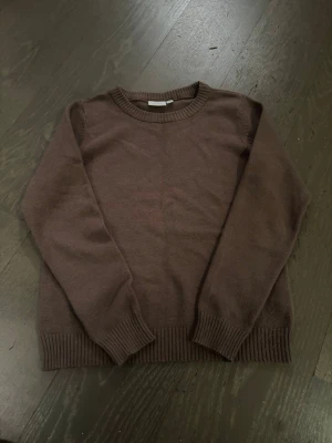 Brun stickad tröja från VILA - Mysig brun stickad tröja från VILA i storlek S. Tröjan har rund halsringning, ribbade muddar vid ärmslut och nederkant samt långärmad passform. Perfekt för lager-på-lager under kyliga dagar.