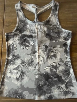 Blommig grå linnetopp från MXIMZE - Säljer en snygg linnetopp från MXIMZE i storlek S. Toppen har ett blommigt mönster i olika grå nyanser och är ärmlös med racerback-design. Perfekt för träning eller chill dagar. Materialet är mjukt och stretchigt, troligen polyester. #MXIMZE tryckt längst ner.