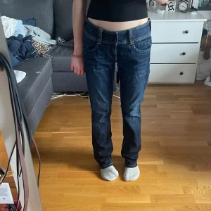 Mörkblå jeans från Pepe Jeans - Midjemått: 35cm Innerbensmått: 76,5cm Ytterbemsmått: 98cm Snygga mörkblå jeans från Pepe Jeans med raka ben och klassiska kontrastsömmar. Byxorna har normal midja och raka ben, samt bakfickor med dekorativ söm. Perfekta till vardags för en stilren look.
