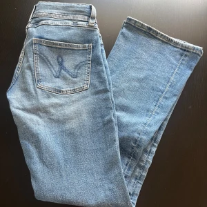 Ljusblå bootcut jeans GinaTricot - Snygga ljusblå jeans från Gina med klassisk femficksdesign och broderad bakficka. Jeansen har bootcut-ben och är tillverkade i mjukt denimtyg som ger en avslappnad känsla. Perfekta för dig som gillar retrovibbar och stilren look.