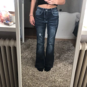 Blå bootcut jeans från Romwe XS - Snygga blå bootcut jeans från Romwe i storlek XS. Jeansen har hög midja, markerade sömmar och slitningar framtill. Baksidan har stora fickor med coola detaljer och dekorationer. Materialet är en klassisk jeansblandning med bomull och polyester.