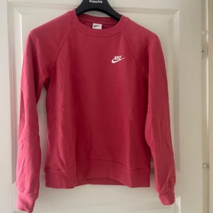 Rosa långärmad Nike sweatshirt - Säljer en snygg rosa sweatshirt från Nike med klassisk logga på bröstet. Tröjan har rund halsringning och långa ärmar, perfekt för en chill och sportig look. Tillverkad i mjuk bomull som känns skön mot huden.