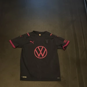 Malmö FF svart matchtröja  - Snygg svart Malmö FF fotbollströja från Puma med rosa detaljer och tryck. Jag har använt den 1 gån när jag gick på en match med en kompis 