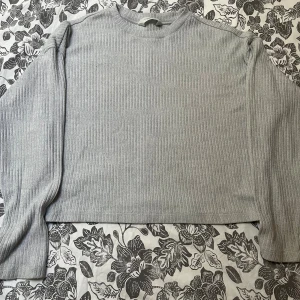 Grå ribbad tröja från H&M - Säljer en grå ribbad tröja från H&M i storlek 158/164. Tröjan har lång ärm, rund halsringning och är tillverkad i mjukt material. Enkel och stilren modell som är lätt att matcha med olika outfits.