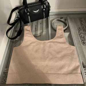 Beige ribbad linnetopp - Snygg beige ribbad träningstopp från BikBok i stretchigt material. Toppen har breda axelband och en croppad passform som sitter tajt mot kroppen. Perfekt till träning. Storlek XS/S.