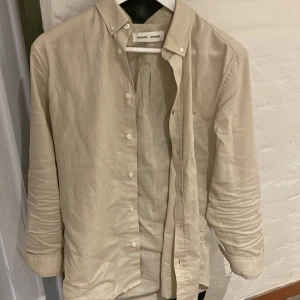 Beige linneskjorta från Samsøe Samsøe - Snygg beige skjorta från Samsøe Samsøe i mjukt linne. Klassisk modell med knappar framtill och button-down krage. Långärmad och med avslappnad passform, perfekt för en chill och stilren look. Tveka inte på att höra av dig vid frågor. Nypris:1,2