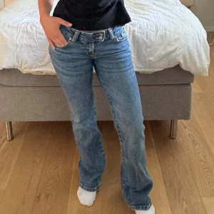 Blå bootcut jeans med låg midja - Snygga blå jeans med bootcut passform och låg midja. Dubbla knappar i midjan, moderna jeans som passar till allt!