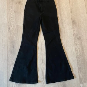 Svarta bootcut jeans från Cider XXS - Svarta jeans från Cider i modellen bootcut med hög midja. Byxorna har klassisk femficksdesign och vida ben som ger en snygg siluett. Tillverkade i denim med en stilren look, perfekta för dig som gillar trendiga och bekväma byxor. Byxorna är oanvända, så i väldigt fint skick! 
