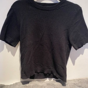 Svart stickad tröja🍁🍂xs - En svart stickad topp från Gina Tricot i storlek XS. Toppen har rund halsringning och korta ärmar, med ribbade kanter vid hals, ärmslut och nederkant. Enkel och stilren modell som är lätt att matcha med olika outfits. Orginal pris 299