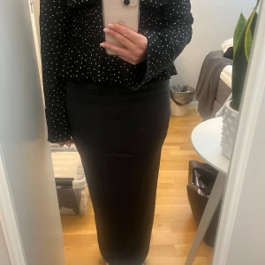 Mörkgrå långkjol med drapering - Säljer en mörkgrå långkjol i mjukt tyg med snygga draperingar längs sidan. Kjolen har en tight passform. Storlek xxs, använd några gånger men mycket fint skick