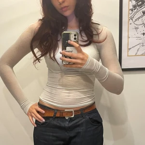 Vit långärmad topp - Säljer en vit, tight mesh topp med lång ärm och rund hals. Toppen är genomskinlig och sitter figurnära, perfekt att styla med linne eller bralette under. Enkel och stilren design som passar till många olika looks. Jättemjuk & bekväm 