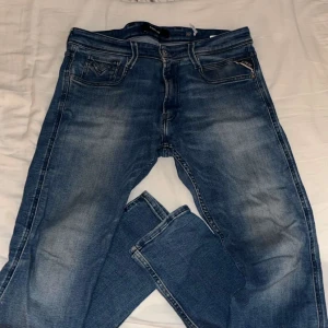 Replay jeans - Snygga blå jeans från Replay med klassisk femficksdesign och raka ben. Jeansen har diskreta slitningar och ljusare partier framtill och baktill för en cool, avslappnad look. Perfekta till sneakers eller boots.