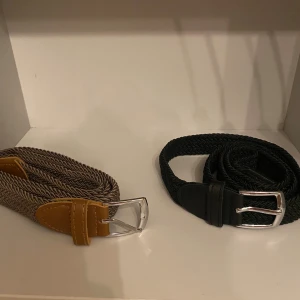 Två flätade bälten i svart och beige - Säljer två snygga flätade bälten, ett i svart med svarta skinn-detaljer och ett i beige med bruna skinn-detaljer. Båda har silvriga spännen och är perfekta för att lyfta vilken outfit som helst. Passar både jeans och chinos.