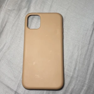 iPhone 11/12 Silikonskal Beige - Beige silikonskal för iPhone 11. Mjukt yttre och fodrad insida för extra skydd. Några mindre märken och lätt slitage syns, men överlag i gott skick. Perfekt för dig som vill skydda din iPhone med stil.