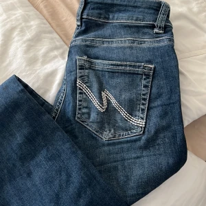 Blå jeans från Nelly med broderad ficka - Snygga blå jeans från Nelly i klassisk denim med vit broderad detalj på bakfickan. Modellen har normal passform och raka ben. Jeansen har fem fickor, bälteshällor och stängs med dragkedja och knapp. Perfekta till sneakers eller boots.
