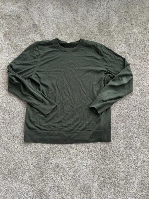 Mörkgrön stickad tröja från Arket - En stilren mörkgrön stickad tröja från Arket med rund halsringning och långa ärmar. Tröjan har ribbade muddar vid hals, ärmslut och nederkant. 100 % ull. Vid frågor är det bara att slänga iväg ett meddelande!