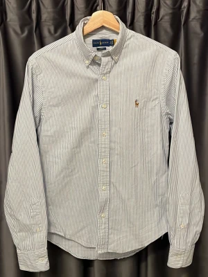 Ralph lauren skjorta  - Ralph lauren skjorta - vit/blå randig - skick 9/10, inga varken skavanker eller slitage - storlek S, men passar XS då den är uppsydd, den var med om en liten olycka så vi behövde kapa ett par cm, men nu blev den för kort - riktigt fet och fräsch skjorta hur som helst - hör av er vid frågor🙌