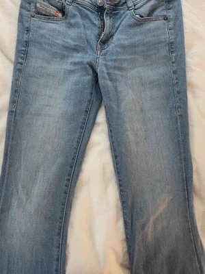 Ljusblå bootcut jeans från Diesel - Snygga ljusblå jeans från Diesel! Jeansen är lågmidjade och bootcut, de har en liten fläck på ena benet men inget man tänker på alls! Dom är lite slitna längst ner men heller inget man tänker på!💞 Ny pris 1500