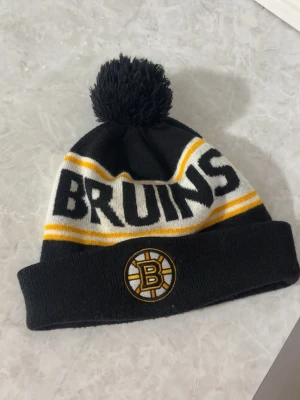 Boston Bruins mössa  - Svart Boston Bruins (NHL) mössa med tofs köpt i USA med både loggan och lagnamnet 