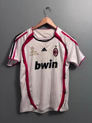 AC Milan fotbollströja Kaka 22 Adidas - Säljer en vit AC Milan fotbollströja från Adidas med röda och svarta detaljer. Tröjan har trycket 'KAKA 22' på ryggen och Bwin-logga på framsidan. Korta ärmar och klubbmärke på bröstet. Perfekt för dig som älskar fotboll och vill ha en ikonisk supportertröja. Är från fotbollsmarknaden! Tillkommer även shorts 