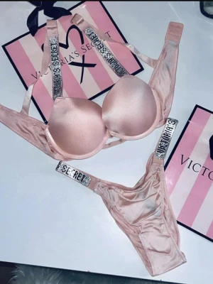 SÖKER!! Rosa set från Victoria's Secret - SÖKER!! Snyggt rosa underklädesset från Victoria's Secret med push-up bh och matchande trosa. Setet har glittriga axelband och detaljer med texten 'SECRET'. Materialet är glansigt och känns lyxigt mot huden. Perfekt för dig som vill känna dig extra fin. Helst nytt eller mycket bra skick. Storlek 70A/75A på bh-n och S/M på trosorna.