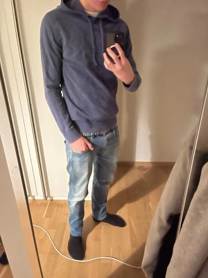 Blå merinoull hoodie - En stilren mörkblå hoodie med huva och dragsko. Hoodien har ribbade muddar vid ärmslut och nederkant, samt en avslappnad passform. Perfekt för en chill och casual look. Materialet känns mjukt och bekvämt mot huden.
