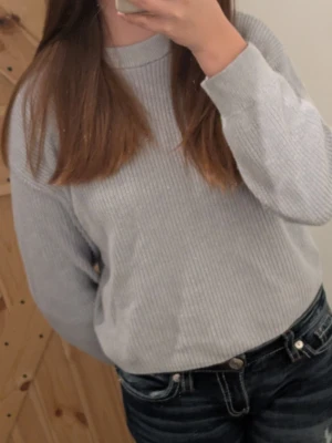 Ljusgrå ribbad långärmad topp - Mysig ljusgrå stickad tröja med rund hals och långa ärmar. Tröjan har ribbstickade muddar vid ärmslut och nederkant,jag är 159cm och den sitter bra och har en bra längd!.