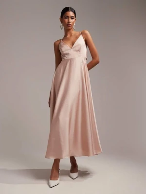 Ljus champagnefärgad långklänning,  - Elegant långklänning i ljus champagnefärg med v-ringad omlott och smala axelband. Klänningen har en flowy siluett och är tillverkad i ett glansigt satinliknande material som ger en lyxig känsla. Perfekt för speciella tillfällen. Helt ny. 