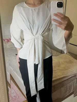 Beige blus med knytband i midjan - Jättefin beige blus från Chiara Forthi. Blusen har  trekvartsärmar och ett brett knytband i midjan som ger en snygg hour-glass figur. Blusen har både öppning framtill och där bak vilket ger en unik touch. Toppen kan framkomma lite see-trough så ha de i åtanke💗