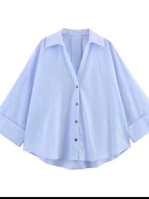 Ljusblå oversized skjorta - Snygg ljusblå skjorta med oversized passform och vida ärmar. Skjortan har klassisk krage, knappar framtill och uppvikta ärmslut. Perfekt för en avslappnad och trendig look.