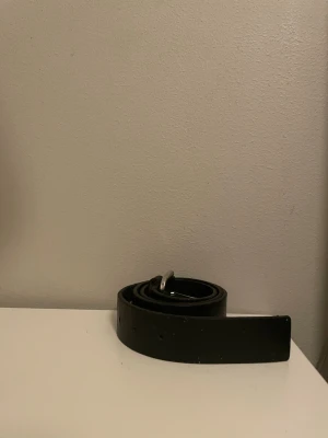 Svart läderbälte Tommy Jeans - Snyggt svart bälte i äkta läder från Tommy Jeans. Klassisk design med silverfärgat, fyrkantigt spänne där loggan är ingraverad. Perfekt accessoar för att lyfta vilken outfit som helst.