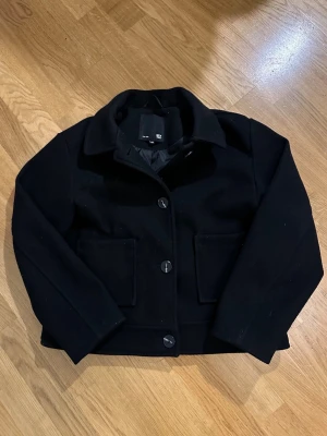Kort kappa/ jacka / skepparkavaj - Svart kort kappa från Lager 157 i storlek 150. Kan även beskrivas som jacka, ytterplagg, höstjacka, vårjacka, ullkappa, kort jacka eller kavajliknande jacka. Knappar framtill och stora fickor fram. Mycket bra skick, kan finnas lätt nopprighet på vissa ställen. ✅välj gärna Instabox💗✅