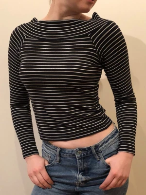Svartvit randig långärmad topp - Svart långärmad topp med vita smala ränder i ribbat bomull. Toppen har en rundad, bred halsringning som ger en elegant look. Barnstorlek 164 - passar S