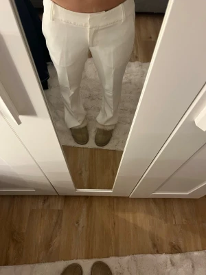 Vita kostymbyxor med raka ben - Säljer ett par stilrena vita kostymbyxor från bikbok med raka ben och låg midja. Byxorna har bälteshällor, diskreta fickor bak och klassisk passform. Perfekta för en clean och fräsch look. Byxorna är endast använda en gång.