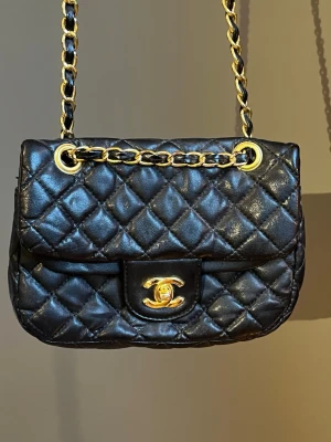  Svart quiltad handväska - Säljer en ikonisk svart quiltad handväska med klassiskt guldigt CC-spänne och kedjerem i guld och svart läder. Väskan har en tidlös design med lock och elegant struktur, perfekt för dig som vill ha en lyxig accessoar med statement-känsla. Köpt i spanien, o den har aldrig använts🖤