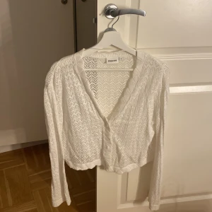 Vit spetsig blus från Kappahl - Säljer en vit kofta från Kappahl i storlek S. Koftan är croppad med lång ärm, v-ringad och har knappar framtill. Materialet är spetsigt och stickat med ett snyggt mönster. Perfekt för dig som gillar romantiska och trendiga detaljer. Nypris 399💕