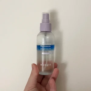 Budgie Niacinamide Face Serum Mist - Fräsch ansiktsmist från Budgie med niacinamid. Kommer i en genomskinlig plastflaska med lila spraykork. Perfekt för att återfukta och ge glow till huden under dagen. Enkel att ta med i väskan och använda när som helst. Se bild för använd mängd. 