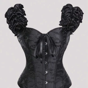 Svart korsett med volangärmar - Säljer en svart korsett med glansiga volangärmar och vackert broderat mönster. Toppen har snörning både fram och bak samt dekorativa knappar framtill. Materialet är glansigt och ger en lyxig känsla. Perfekt för dig som vill sticka ut med en edgy och unik look. Helt oanvänd!