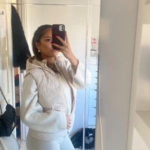 Cremevit/Beige väst med luva - En Cremevit/beige väst med luva som aldrig använts. Funkar för folk med både S och XS💕