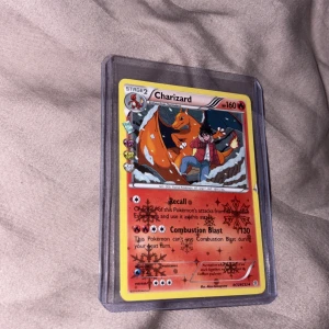 Charizard - Cool Pokémon-kort med Charizard och tränare i action! Perfekt för dig som älskar samlarkort, Pokémon och episka strider. Kortet är i skyddande plastfodral och har snygg design med specialeffekter. Ett måste för unga samlare och fans av Pokémon-världen!