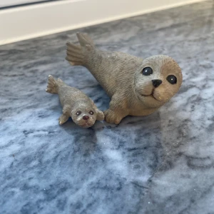 2 söta sälfigurer - Två söta sälfigurer, en större och en mindre, perfekta som dekoration eller leksak. Figurerna har fina detaljer och är i gott skick med endast mindre tecken på slitage. Passar samlare eller som prydnad i hemmet.