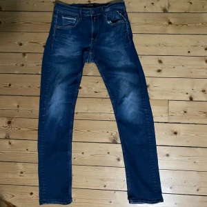 Replay Hyperflex Grover jeans blå - Säljer ett par Replay Hyperflex Grover jeans i klassisk blå tvätt. De är storlek 29 32. Jeansen har raka ben, fem fickor och snygga detaljer vid fickorna. Materialet är stretchigt för extra komfort och passformen är normal. Perfekta för dig som gillar stilrena och bekväma jeans. De har dock ett litet hål vid grenen men borde inte vara så svårt att laga. Perfekta inför hösten!🔥